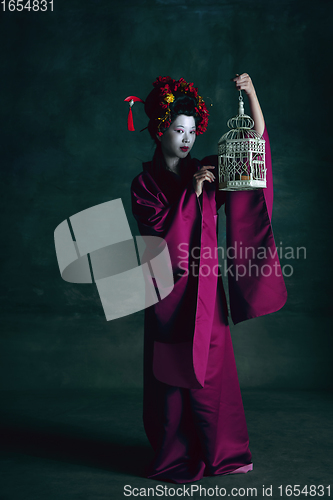 Image of Young japanese woman as geisha on dark green background. Retro style, comparison of eras concept.