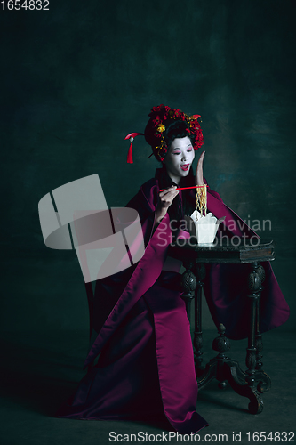 Image of Young japanese woman as geisha on dark green background. Retro style, comparison of eras concept.