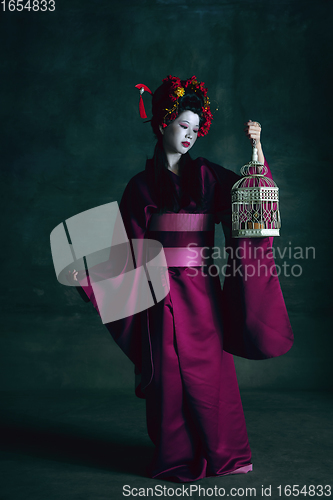 Image of Young japanese woman as geisha on dark green background. Retro style, comparison of eras concept.