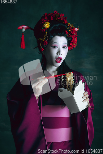 Image of Young japanese woman as geisha on dark green background. Retro style, comparison of eras concept.