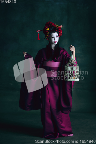 Image of Young japanese woman as geisha on dark green background. Retro style, comparison of eras concept.