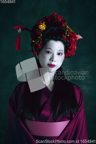 Image of Young japanese woman as geisha on dark green background. Retro style, comparison of eras concept.