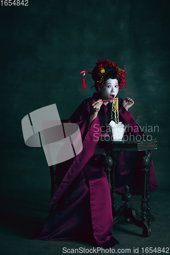 Image of Young japanese woman as geisha on dark green background. Retro style, comparison of eras concept.