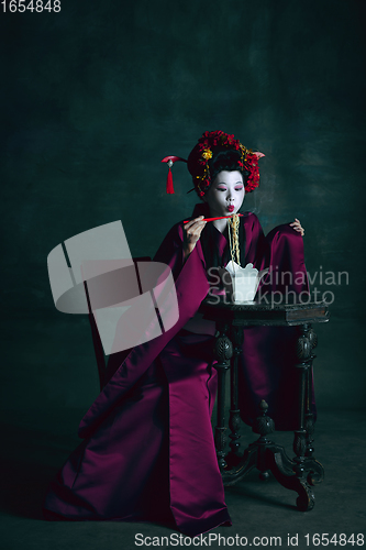 Image of Young japanese woman as geisha on dark green background. Retro style, comparison of eras concept.