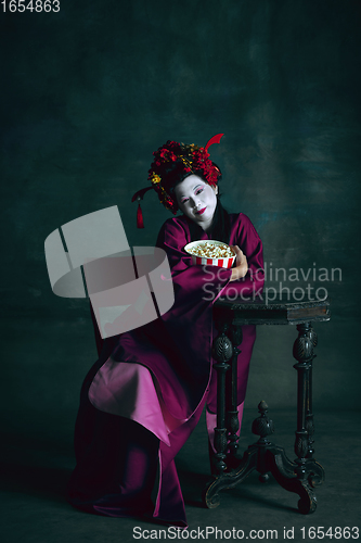 Image of Young japanese woman as geisha on dark green background. Retro style, comparison of eras concept.