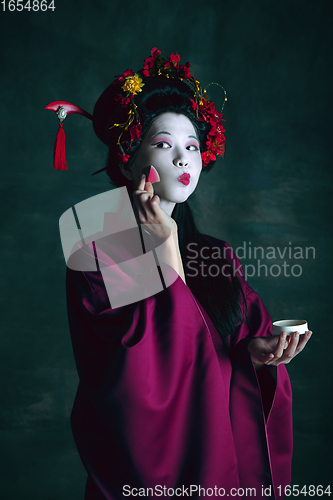 Image of Young japanese woman as geisha on dark green background. Retro style, comparison of eras concept.