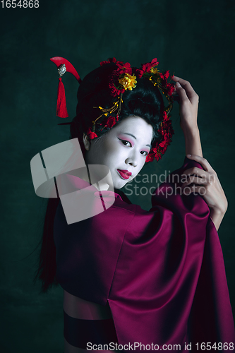 Image of Young japanese woman as geisha on dark green background. Retro style, comparison of eras concept.