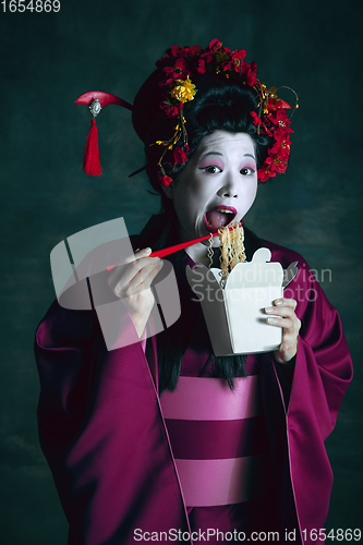 Image of Young japanese woman as geisha on dark green background. Retro style, comparison of eras concept.