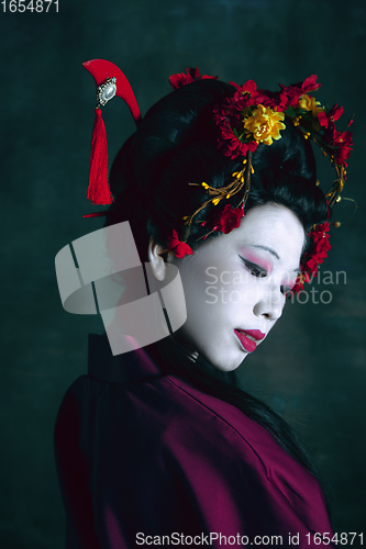 Image of Young japanese woman as geisha on dark green background. Retro style, comparison of eras concept.