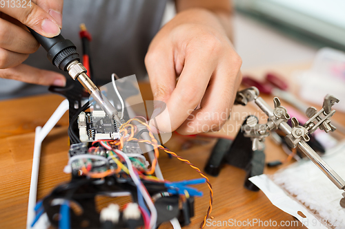 Image of Man using welding for connecting wire on board of the drone