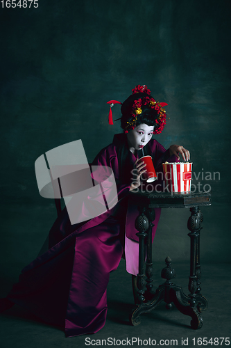 Image of Young japanese woman as geisha on dark green background. Retro style, comparison of eras concept.