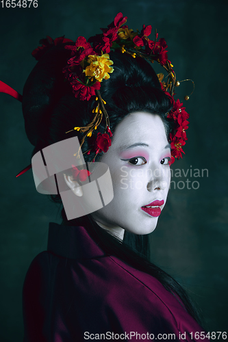 Image of Young japanese woman as geisha on dark green background. Retro style, comparison of eras concept.