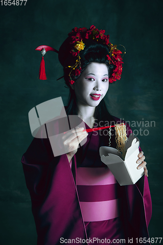 Image of Young japanese woman as geisha on dark green background. Retro style, comparison of eras concept.