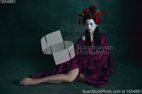 Image of Young japanese woman as geisha on dark green background. Retro style, comparison of eras concept.