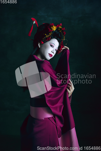 Image of Young japanese woman as geisha on dark green background. Retro style, comparison of eras concept.