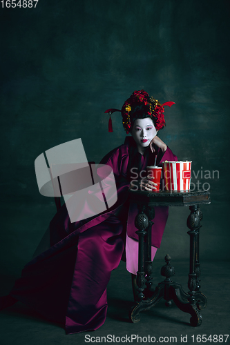 Image of Young japanese woman as geisha on dark green background. Retro style, comparison of eras concept.