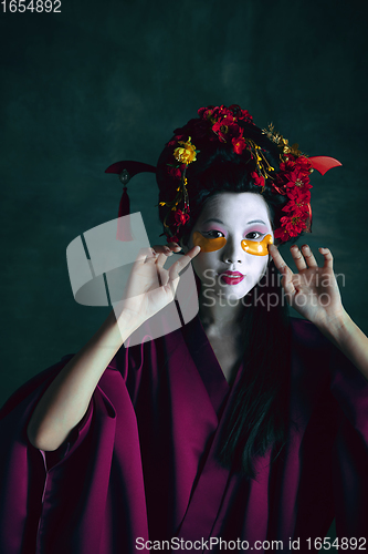 Image of Young japanese woman as geisha on dark green background. Retro style, comparison of eras concept.