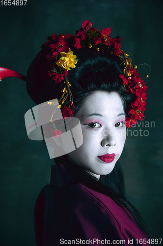 Image of Young japanese woman as geisha on dark green background. Retro style, comparison of eras concept.