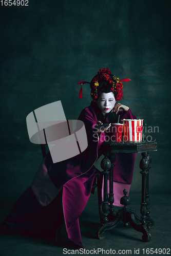 Image of Young japanese woman as geisha on dark green background. Retro style, comparison of eras concept.