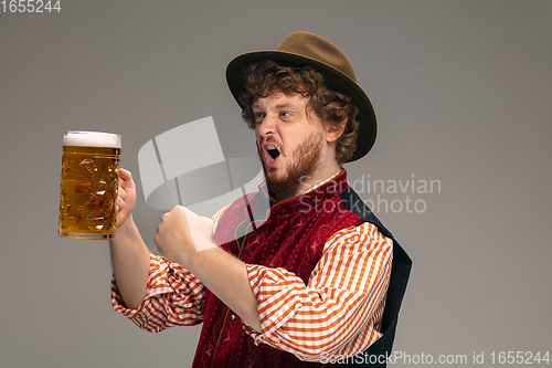 Image of Happy smiling man dressed in traditional Austrian or Bavarian costume gesturing isolated on grey studio background