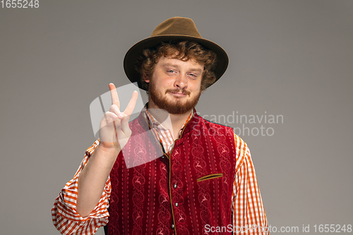 Image of Happy smiling man dressed in traditional Austrian or Bavarian costume gesturing isolated on grey studio background