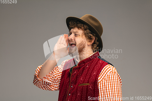 Image of Happy smiling man dressed in traditional Austrian or Bavarian costume gesturing isolated on grey studio background