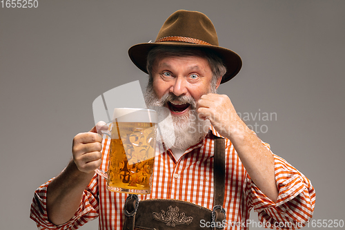 Image of Happy senior man dressed in traditional Austrian or Bavarian costume gesturing isolated on grey studio background