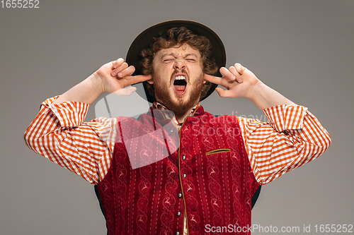 Image of Happy smiling man dressed in traditional Austrian or Bavarian costume gesturing isolated on grey studio background