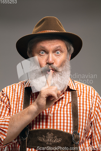 Image of Happy senior man dressed in traditional Austrian or Bavarian costume gesturing isolated on grey studio background