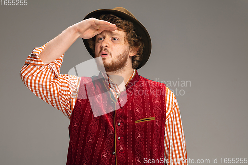 Image of Happy smiling man dressed in traditional Austrian or Bavarian costume gesturing isolated on grey studio background