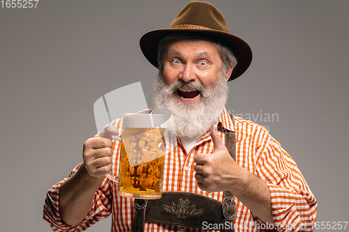 Image of Happy senior man dressed in traditional Austrian or Bavarian costume gesturing isolated on grey studio background