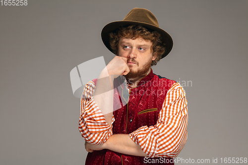 Image of Happy smiling man dressed in traditional Austrian or Bavarian costume gesturing isolated on grey studio background