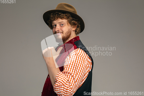 Image of Happy smiling man dressed in traditional Austrian or Bavarian costume gesturing isolated on grey studio background