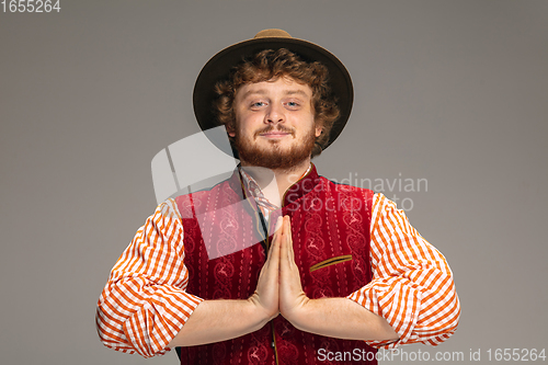 Image of Happy smiling man dressed in traditional Austrian or Bavarian costume gesturing isolated on grey studio background