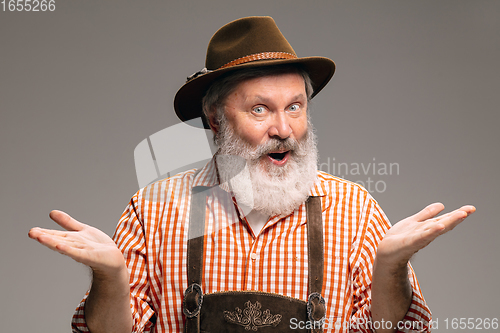 Image of Happy senior man dressed in traditional Austrian or Bavarian costume gesturing isolated on grey studio background