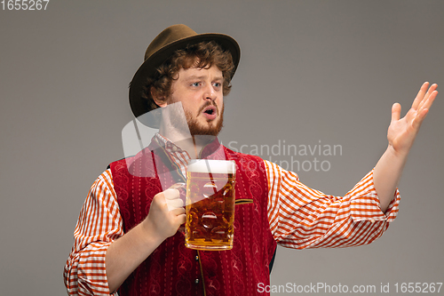 Image of Happy smiling man dressed in traditional Austrian or Bavarian costume gesturing isolated on grey studio background