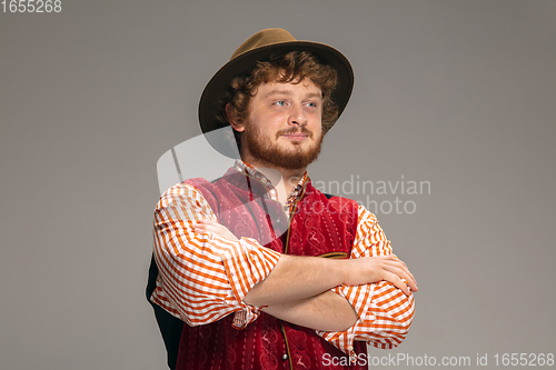 Image of Happy smiling man dressed in traditional Austrian or Bavarian costume gesturing isolated on grey studio background