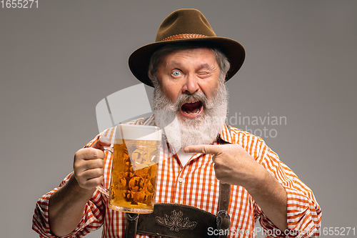 Image of Happy senior man dressed in traditional Austrian or Bavarian costume gesturing isolated on grey studio background