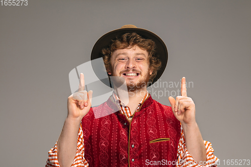 Image of Happy smiling man dressed in traditional Austrian or Bavarian costume gesturing isolated on grey studio background