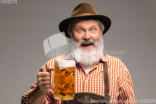 Image of Happy senior man dressed in traditional Austrian or Bavarian costume gesturing isolated on grey studio background