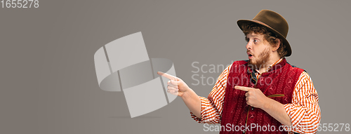 Image of Happy smiling man dressed in traditional Austrian or Bavarian costume gesturing isolated on grey studio background