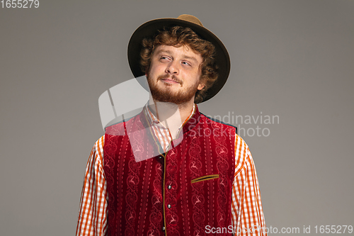 Image of Happy smiling man dressed in traditional Austrian or Bavarian costume gesturing isolated on grey studio background