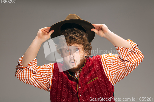 Image of Happy smiling man dressed in traditional Austrian or Bavarian costume gesturing isolated on grey studio background