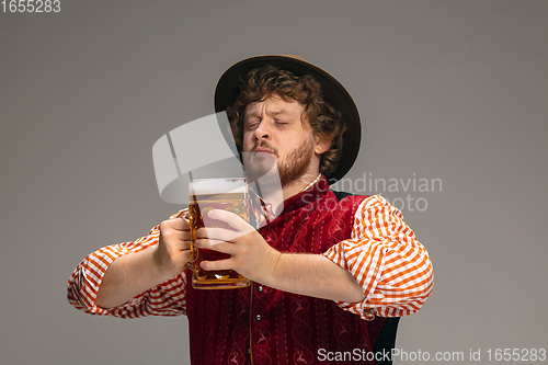 Image of Happy smiling man dressed in traditional Austrian or Bavarian costume gesturing isolated on grey studio background