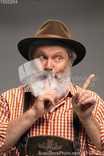 Image of Happy senior man dressed in traditional Austrian or Bavarian costume gesturing isolated on grey studio background