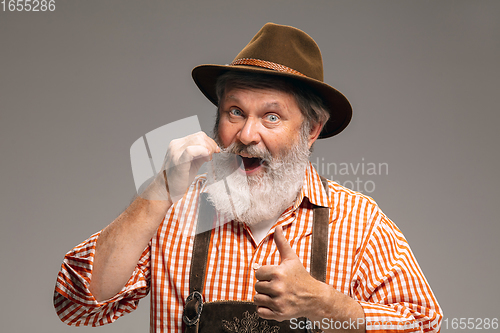 Image of Happy senior man dressed in traditional Austrian or Bavarian costume gesturing isolated on grey studio background