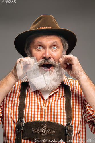 Image of Happy senior man dressed in traditional Austrian or Bavarian costume gesturing isolated on grey studio background