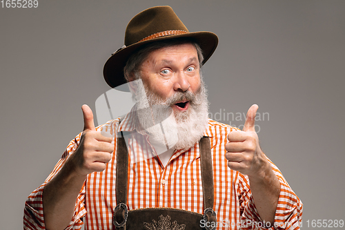 Image of Happy senior man dressed in traditional Austrian or Bavarian costume gesturing isolated on grey studio background