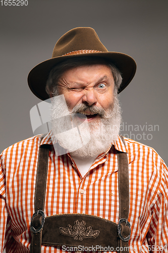 Image of Happy senior man dressed in traditional Austrian or Bavarian costume gesturing isolated on grey studio background