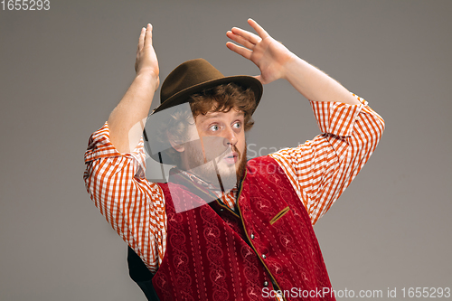 Image of Happy smiling man dressed in traditional Austrian or Bavarian costume gesturing isolated on grey studio background